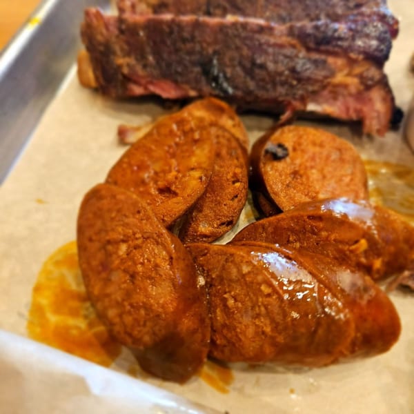 Close-up of sliced, glazed barbecue sausage and ribs on a tray at Barbecue Nation.